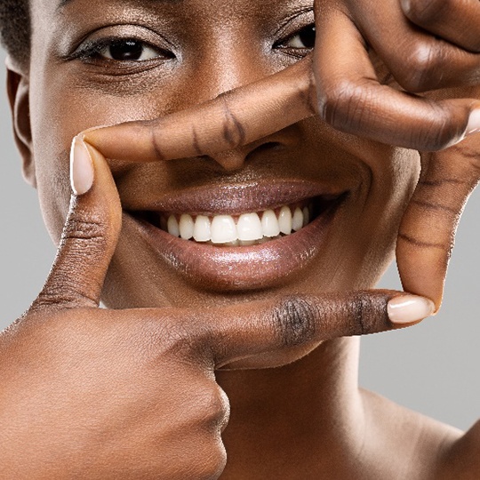 Woman using her fingers to frame her white teeth