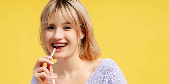 A teen with braces drinking a smoothie