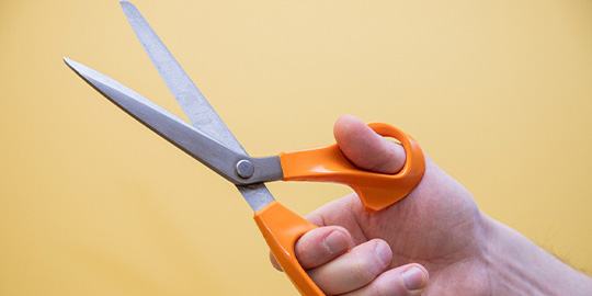 A hand holding a pair of scissors