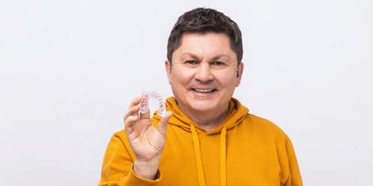 middle-aged man holding Spark Clear Aligner   