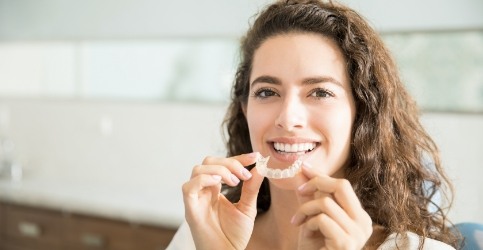 Smiling woman holding an Evoaligner tray