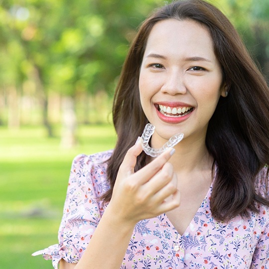 a patient holding her Invisalign aligner in Atlanta