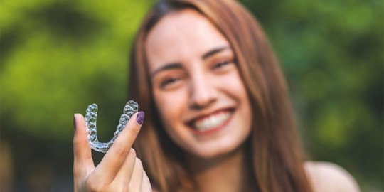 Girl holding Invisalign aligner in Atlanta