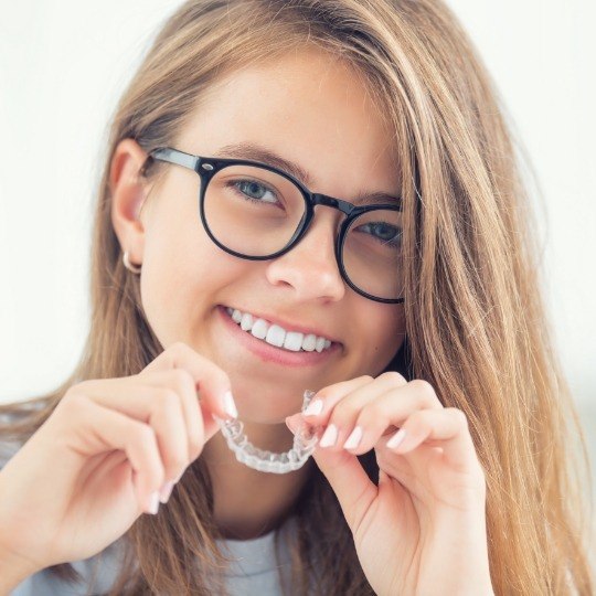 Young woman placing Invisalign teen aligner tray