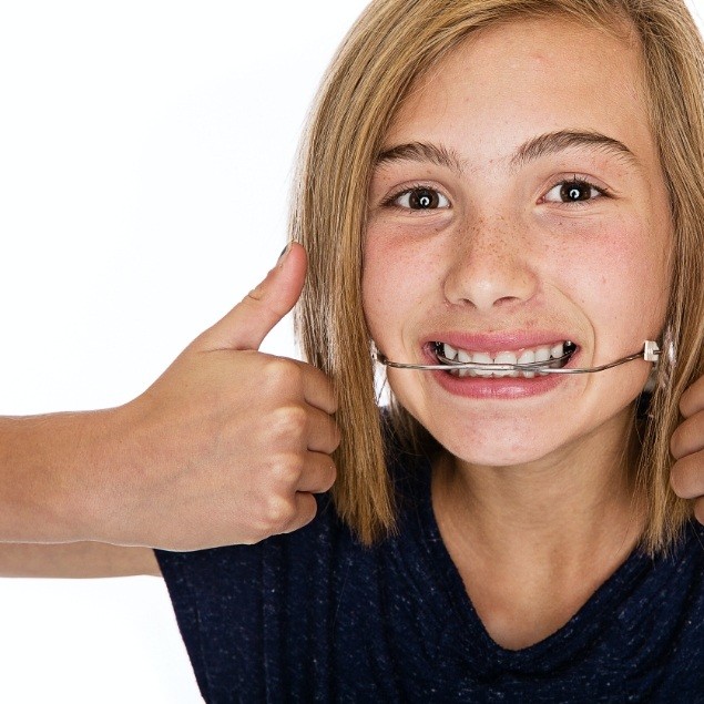 Child receiving dentofacial orthopedics treatment giving thumbs up