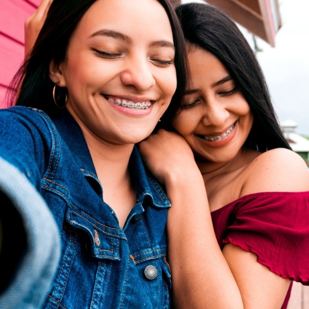 Two smiling teens with traditional braces