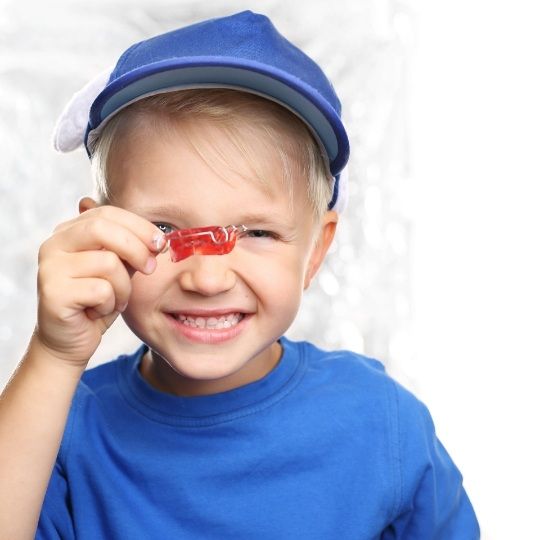 Young boy holding up oral appliance for phase one orthodontic treatment