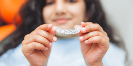 Teen girl holding clear aligner