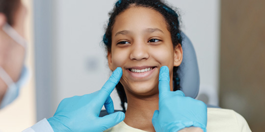 Orthodontist looking at teen girl's smile