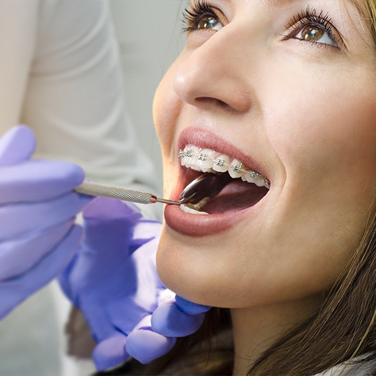 Orthodontist examining patient's smile after traditional braces placement