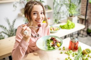 a woman showing her white teeth while eating healthy foods