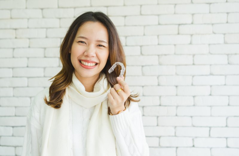 patient holding Invisalign tray and smiling 