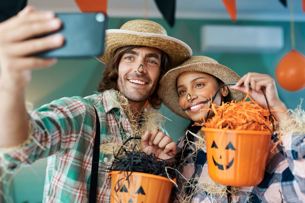 Young couple dressed as scarecrows smiling while taking selfie